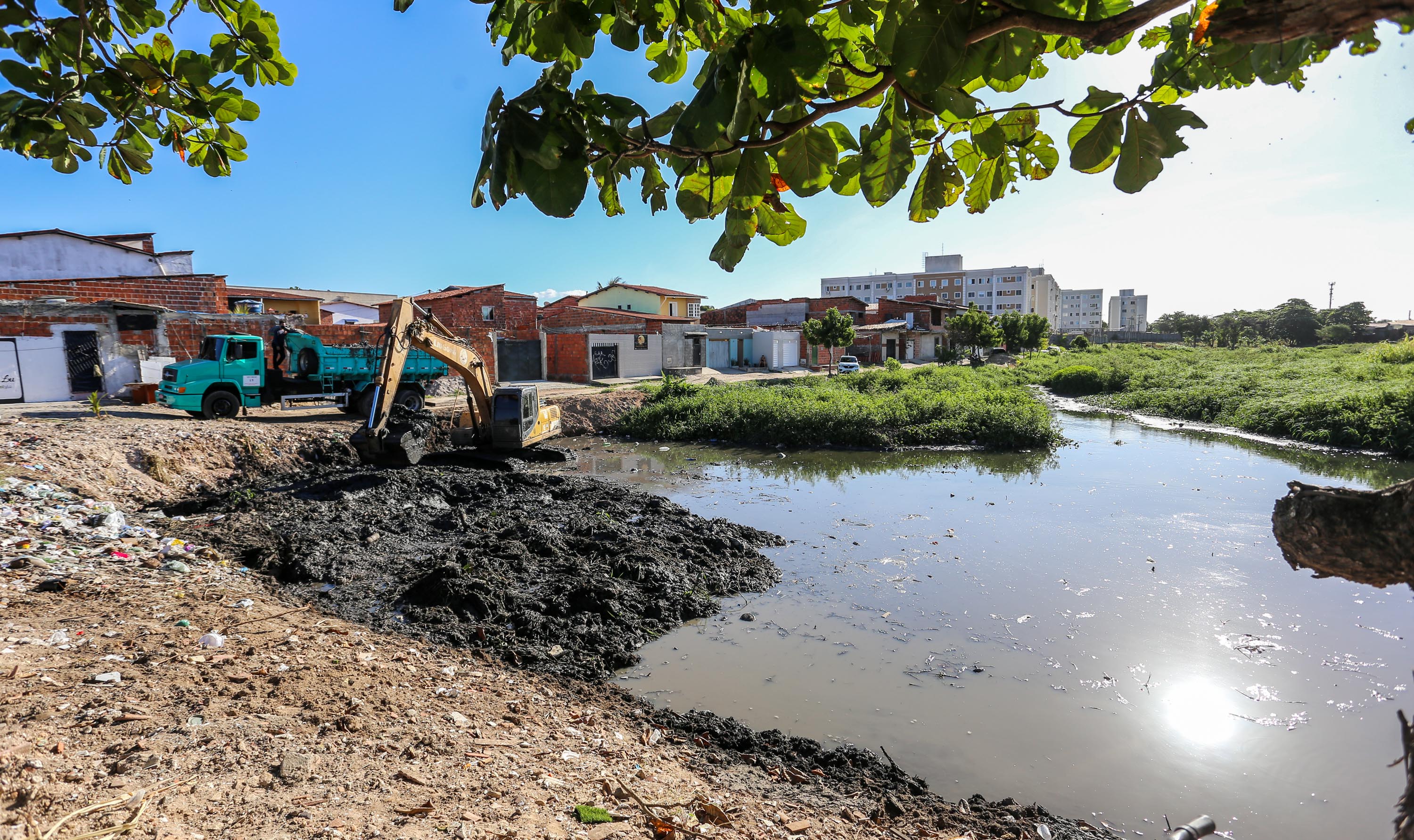 a foto mostra a lagoa seca com uma caminhão e uma retroescavadeira